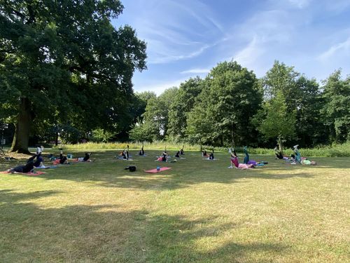 Personen liegen auf Sportmatte in einem Park