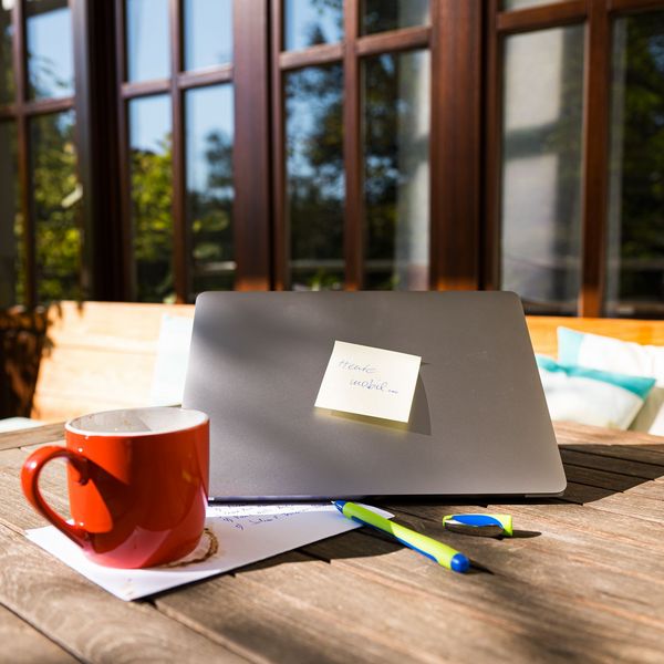 Eine Tasse Kaffe und ein Laptop stehen auf einem Tisch in der Sonne. Auf dem Laptop klebt ein Zetel mit der Aufschrift:"Heute mobil"